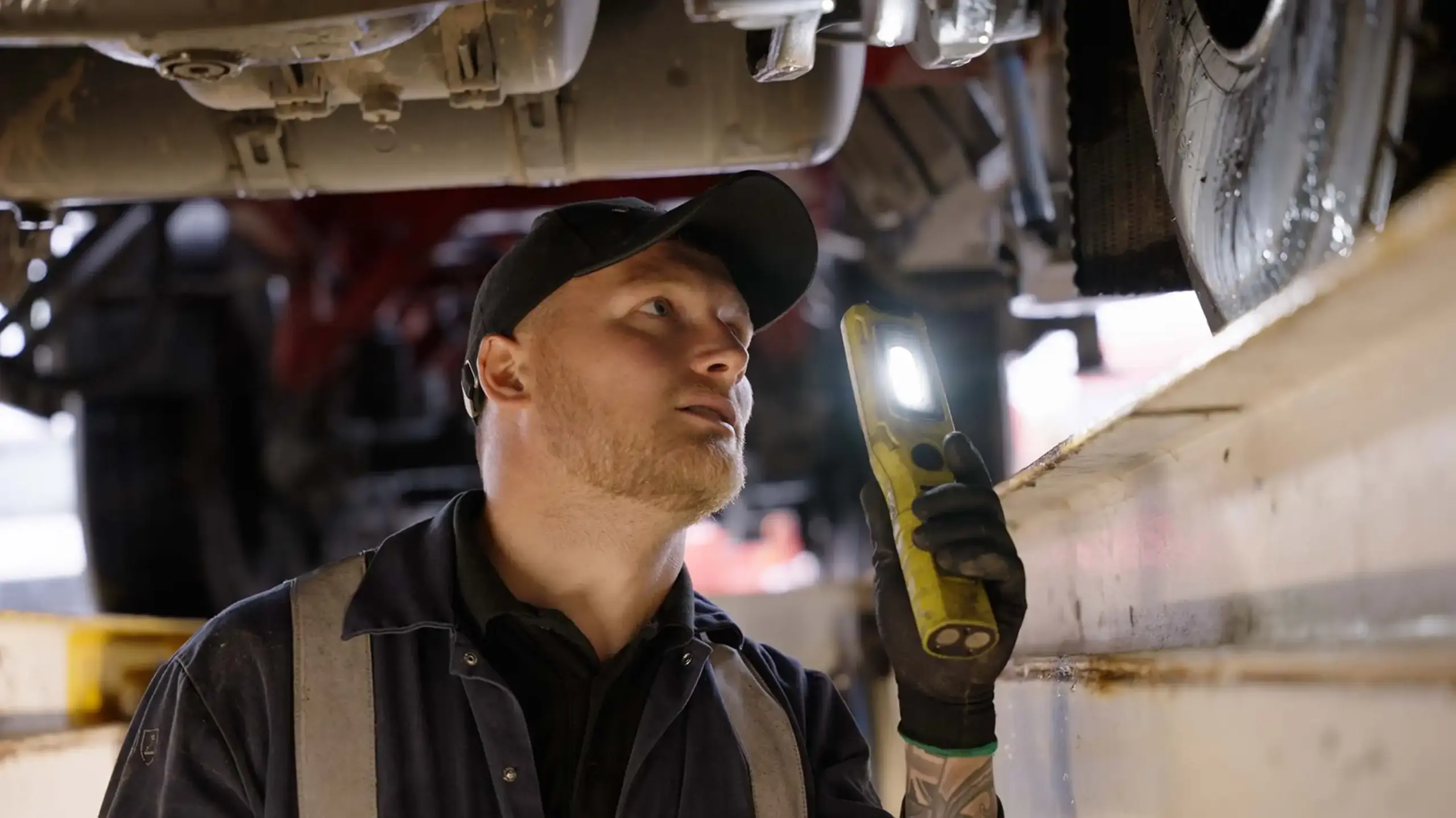 Man looking under a lorry with torch